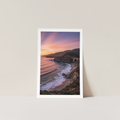 Framed artwork of a coastal landscape with a sunset over the ocean.