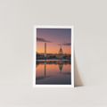 Framed photograph of a cityscape with a sunset reflection on water.