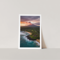 Poster of a sunset over a coastal landscape with a mountain, displayed on a white wall.